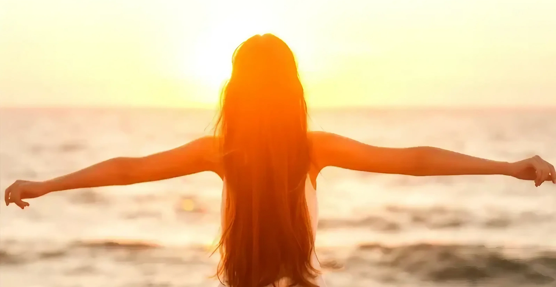 Woman with long hair embracing the sunset by the sea.